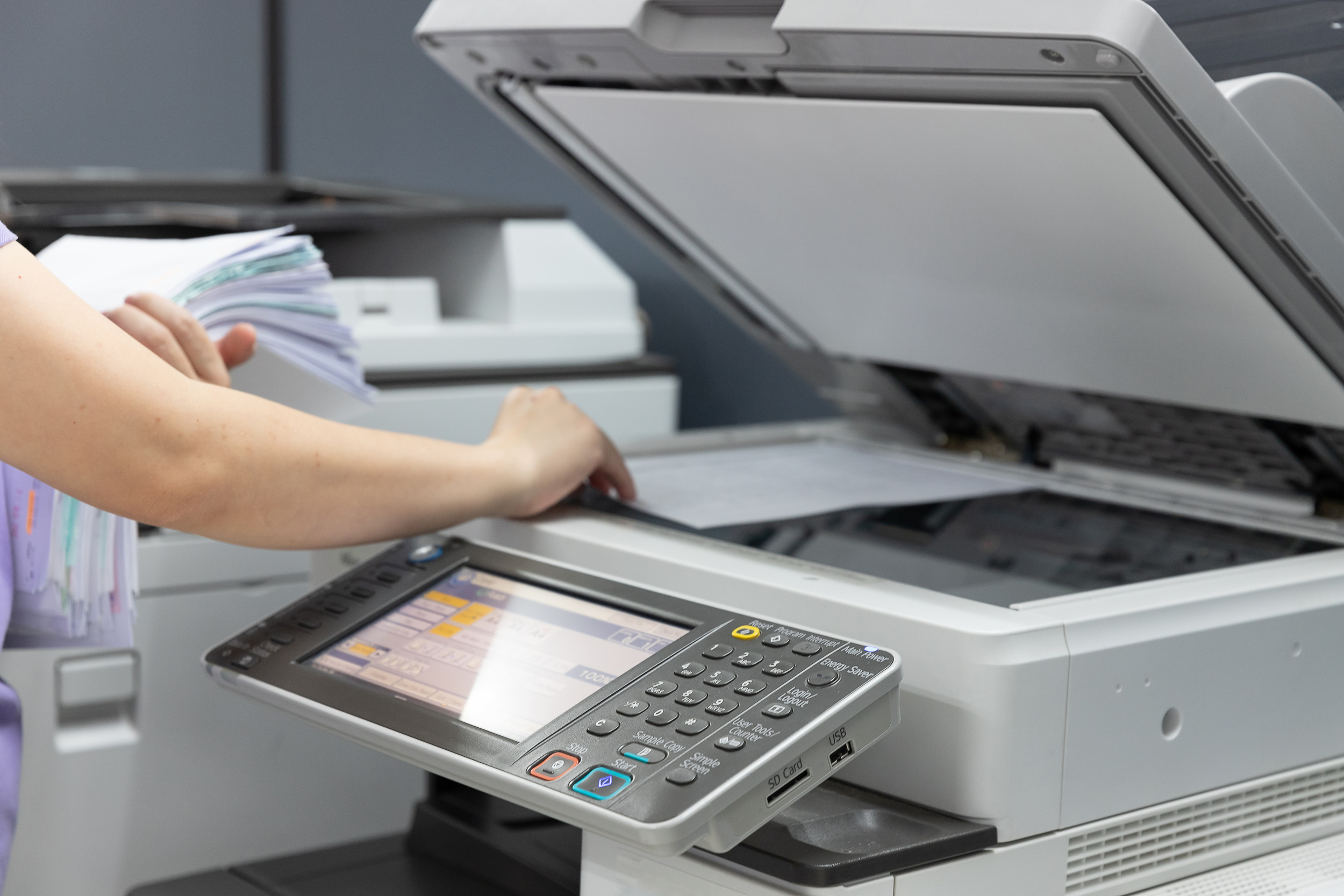 Bussinesswoman using copier machine to copy heap of paperwork in